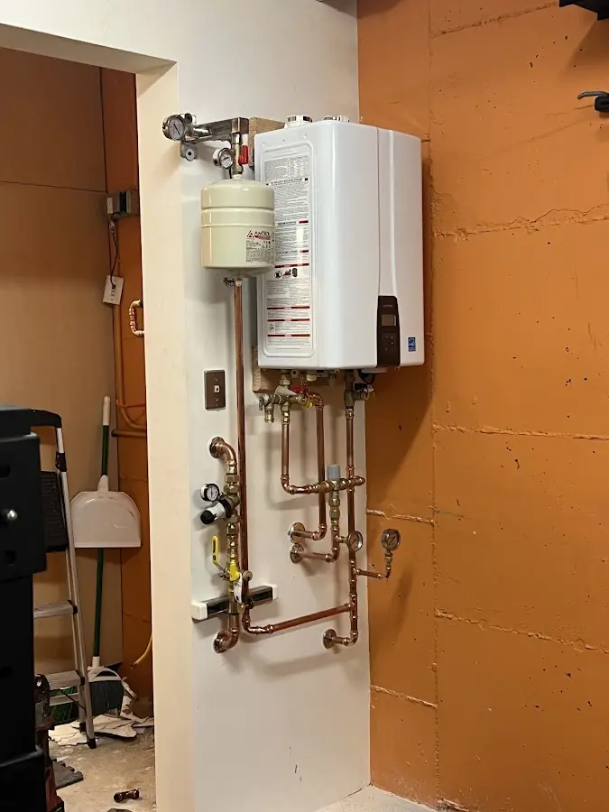Plumbing technician inspecting water heater connections in Creve Coeur